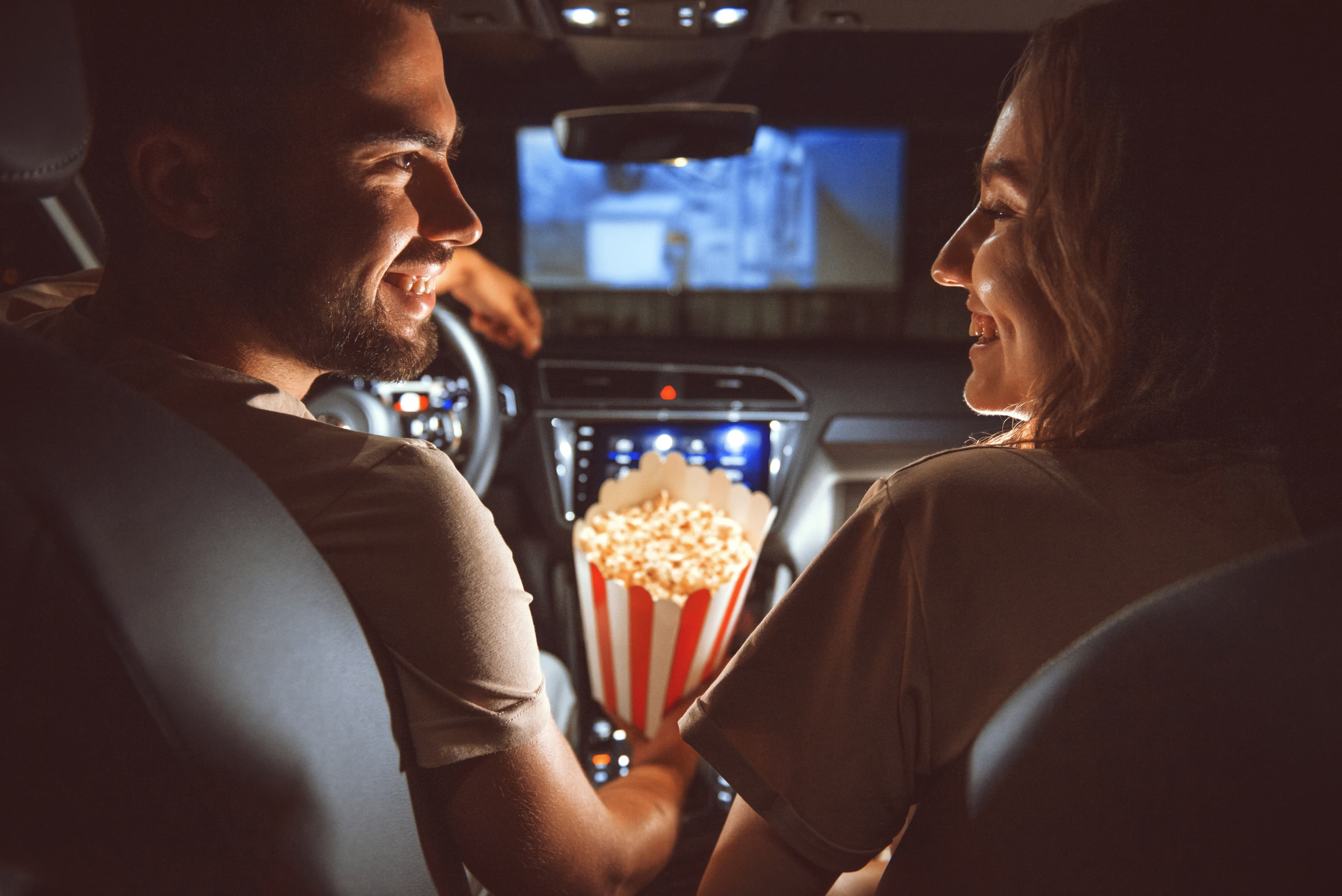 Happy couple smiling inside their car at a drive-in movie theater